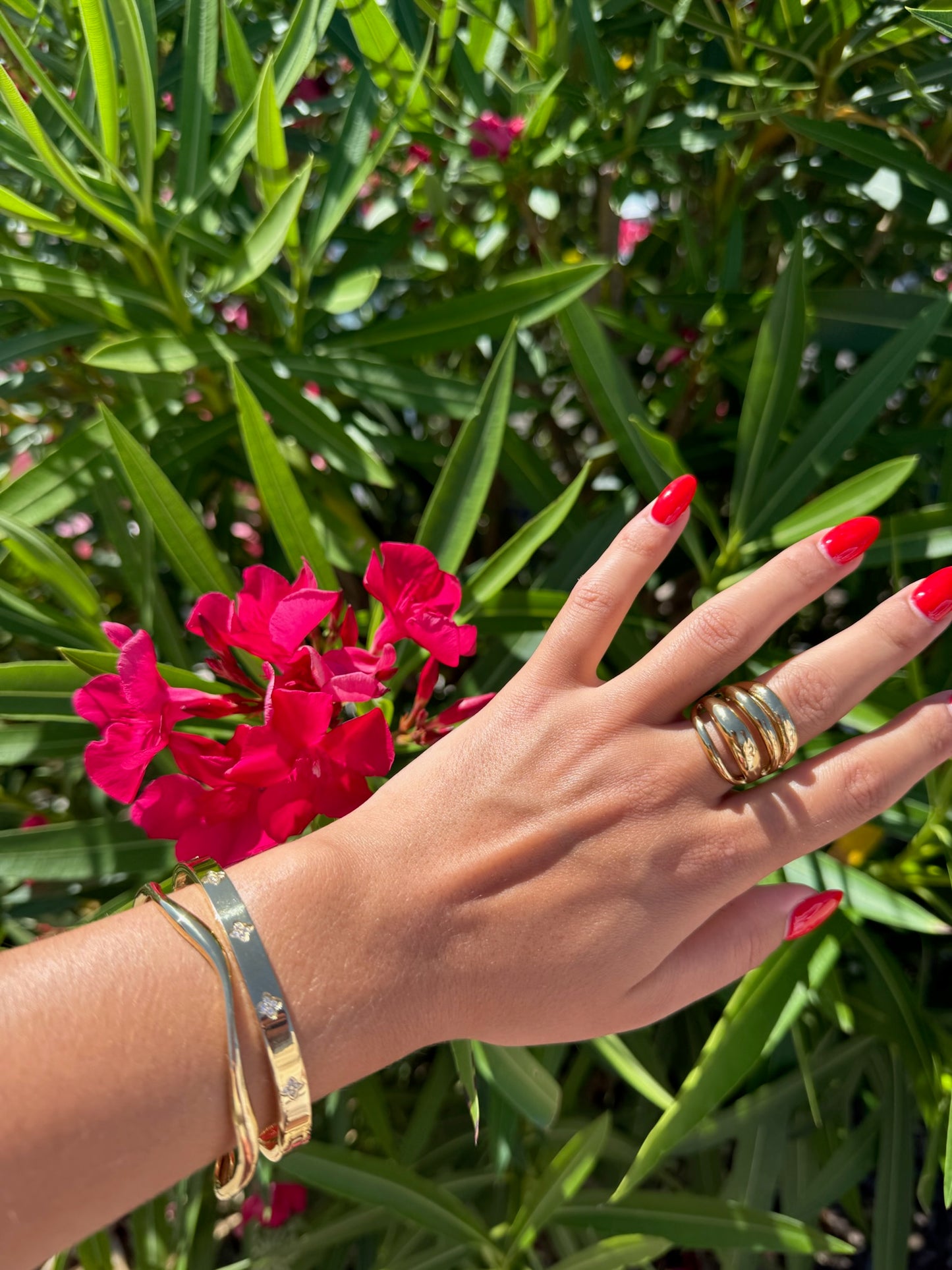 Bracelet doré Ondula en acier inoxydable, au design ondulé et minimaliste, porté avec élégance au poignet sous le soleil, création originale Onaïa Bijoux.