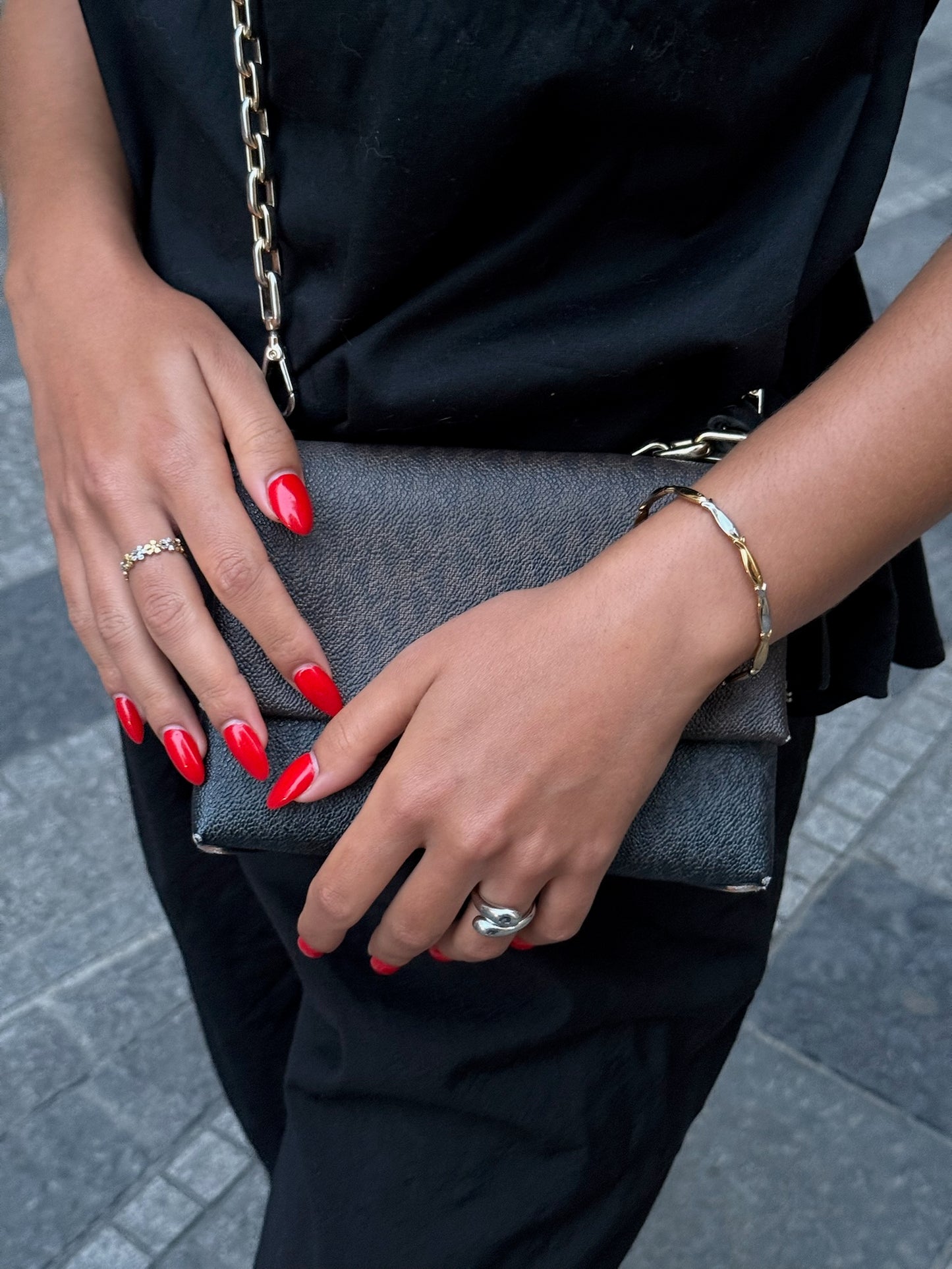 Duo de bagues dorées Solaris, bracelet doré Sardina et bague argentée Fiorina signés Onaïa Bijoux, portés avec une tenue noire et un sac chic.