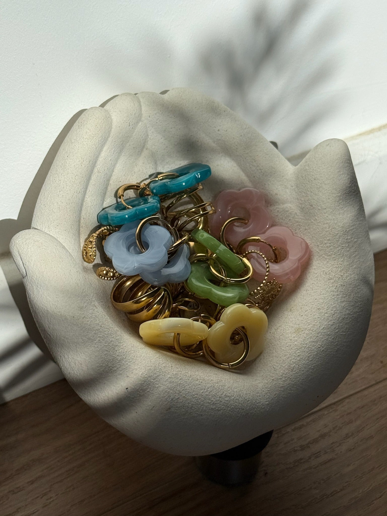 Boucles d'oreilles Flora en acier inoxydable et résine mises en scène dans un récipient en forme de main - Onaïa Bijoux