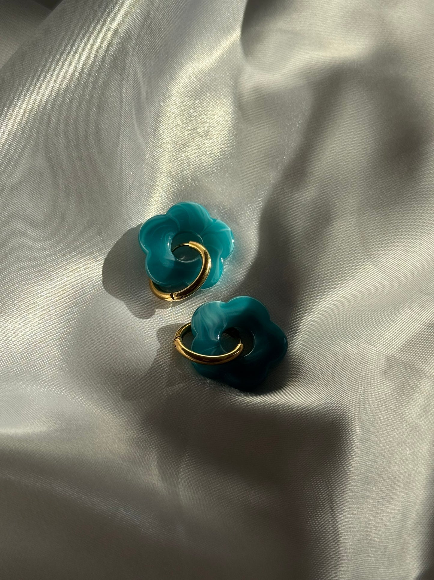 Boucles d'oreilles Flora en résine bleue et acier inoxydable doré sur fond blanc satiné - Onaïa Bijoux