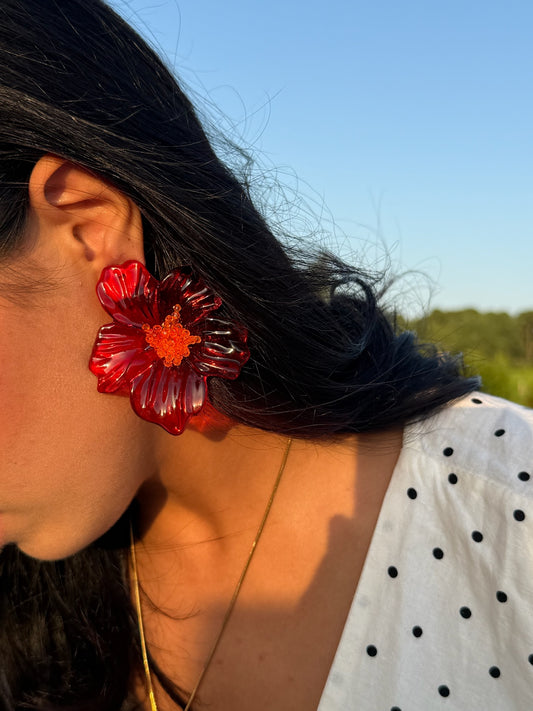 Boucles d'oreilles hibiscus en résine portées dans un décor champêtre, signé Onaïa bijoux