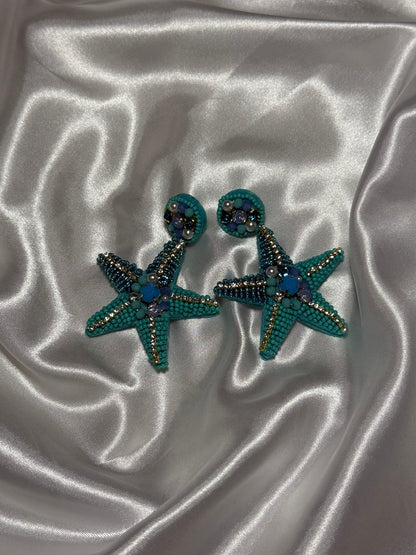 Boucles d'oreilles Sirena en perles bleues en forme d'étoile de mer sur fond blanc satiné - Onaïa Bijoux