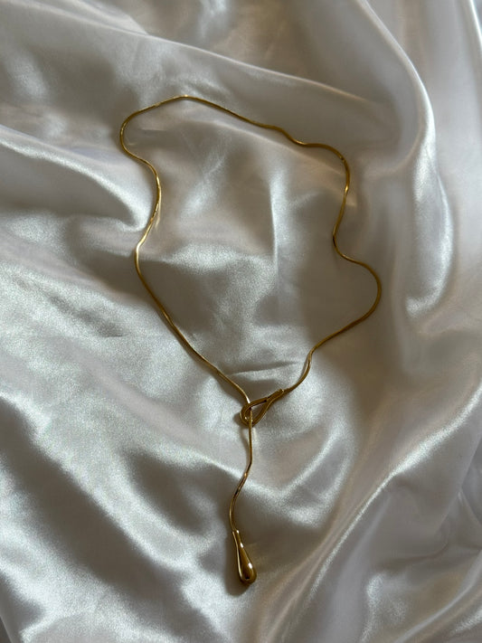Collier Goccia en acier inoxydable doré sur fond blanc satiné, une création signée Onaïa Bijoux