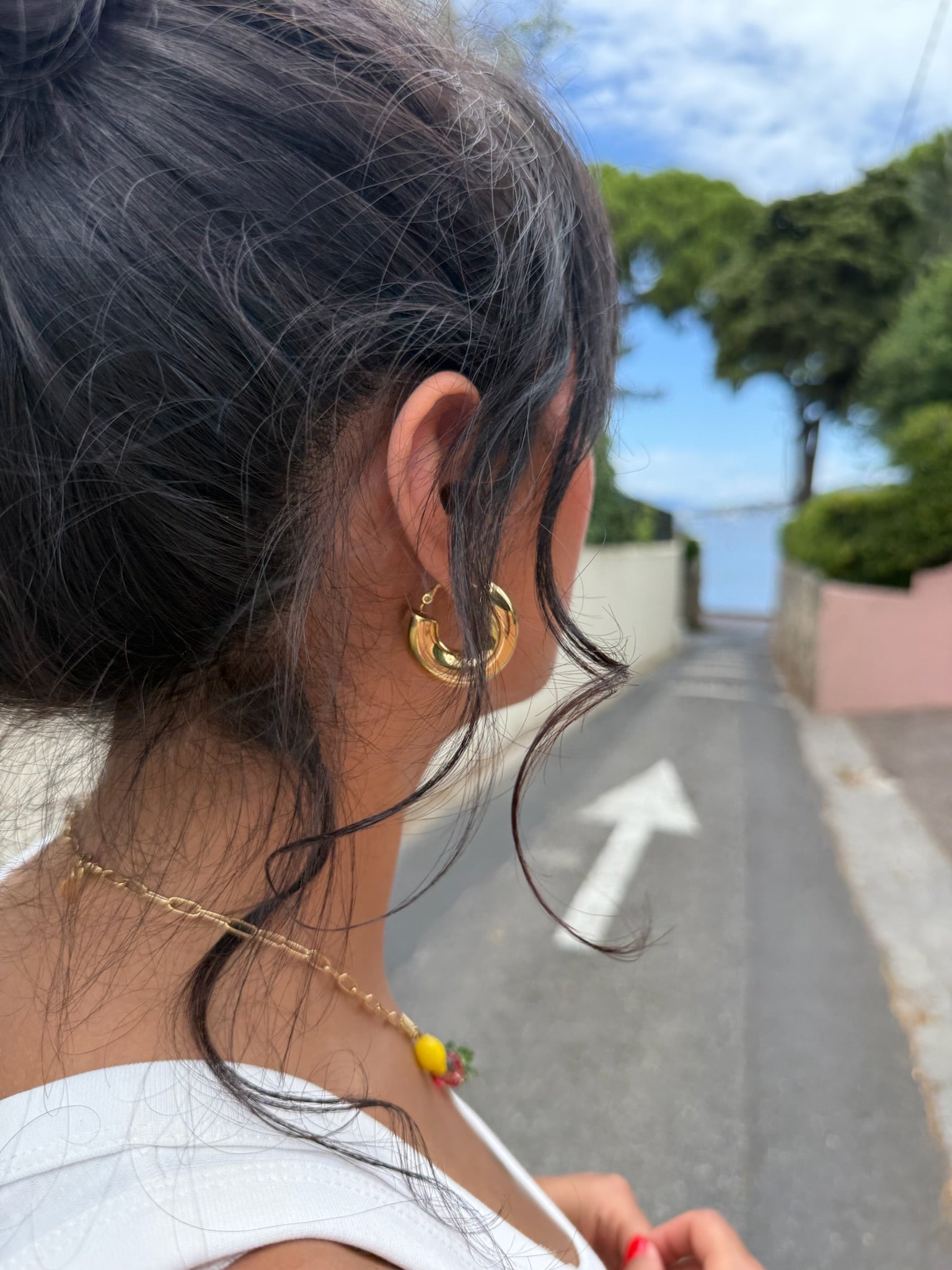 Jeune femme porte des bijoux Onaïa en acier inoxydable et résine en regardant la mer au cap d'Antibes, signé Onaïa bijoux