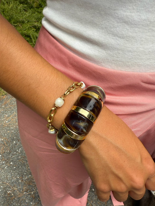Bracelet doré Luce en acier inoxydable orné de perles nacrées, porté au poignet sur une tenue estivale rose, création élégante signée Onaïa Bijoux.