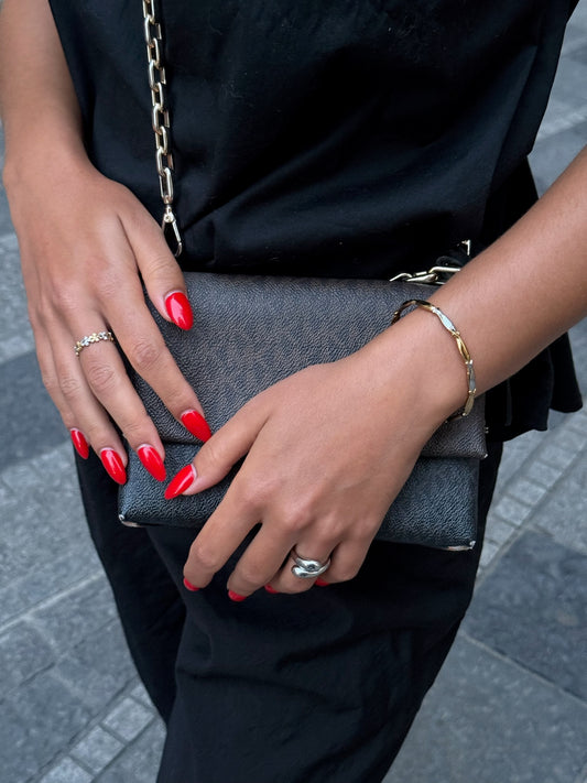 Duo de bagues dorées Solaris, bracelet doré Sardina et bague argentée Fiorina signés Onaïa Bijoux, portés avec une tenue noire et un sac chic.