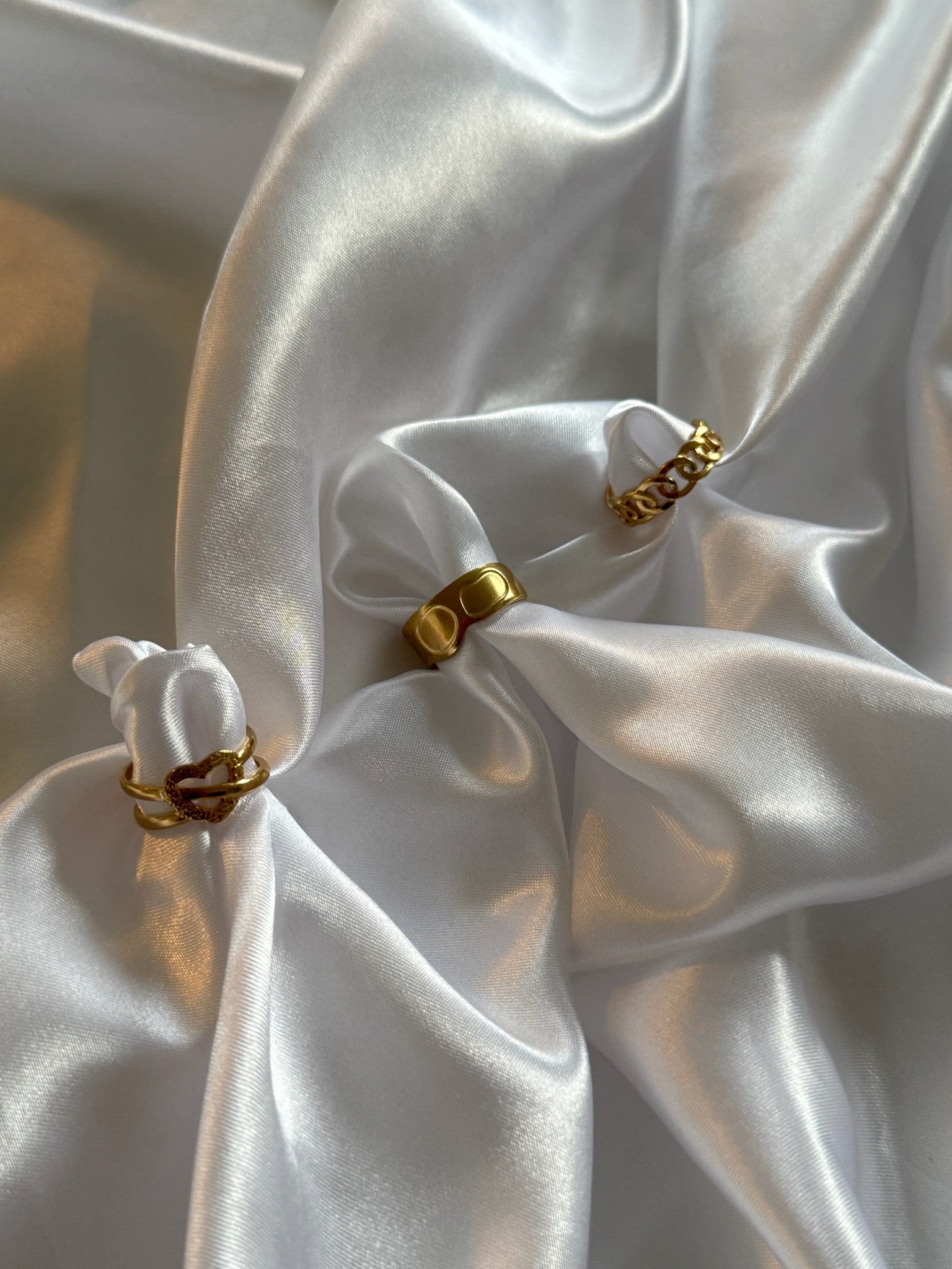 Trio de bagues dorées Trinita en acier inoxydable signé Onaïa Bijoux, présenté sur fond satiné blanc